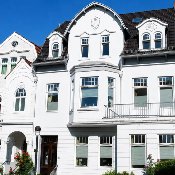 Altbremer Haus von 1904 in Schwachhausen: weiße Putzfassade mit geschwungenem Giebel, Erker und Balkon, daneben das Nachbarhaus derselben Zeile