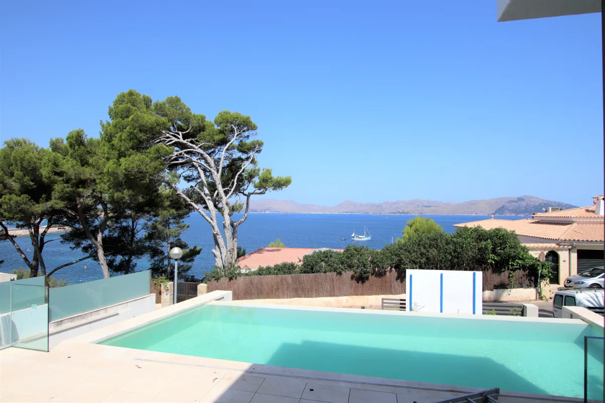 Pool auf der Terrassenebene, dahinter Pinien und die Bucht