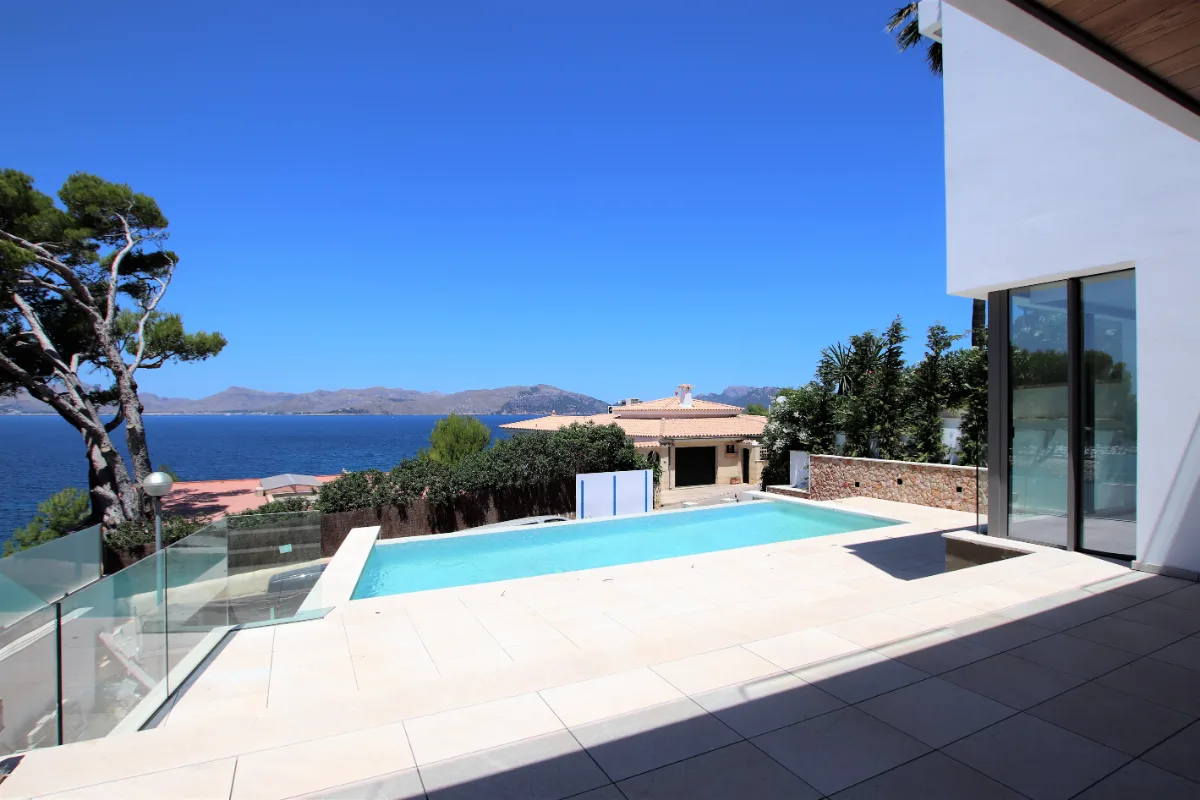 Terrasse des Neubaus mit Pool, dahinter die Bucht und die Berge