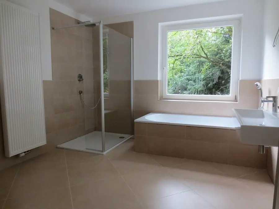 Modernisiertes Bad mit bodengleicher Dusche und Wanne am Fenster